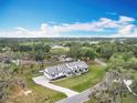 An aerial view of the bright, modern farmhouse-style home on an expansive lush green lawn under a blue sky at 464 Long & Winding Rd, Groveland, FL 34736