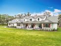 Stunning two-story farmhouse with a metal roof, stone accents, dormer windows, and a welcoming front porch at 464 Long & Winding Rd, Groveland, FL 34736