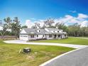 A beautifully landscaped lawn leads to a modern farmhouse-style home with stone accents and a paved driveway at 464 Long & Winding Rd, Groveland, FL 34736