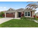 Charming single-story home boasting a well-manicured lawn, vibrant plants, and a convenient two-car garage at 5510 Thome Loop, The Villages, FL 32163