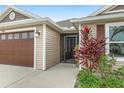 Inviting front entry featuring a secure screen door, lush landscaping, and direct access to the attached garage at 5510 Thome Loop, The Villages, FL 32163