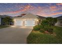 Charming single Gathering home showcasing a well maintained lawn and a two car garage at sunset at 5675 Herman Ave, The Villages, FL 32163