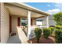 Inviting covered front porch with classic columns, chairs, and meticulous landscaping at 5675 Herman Ave, The Villages, FL 32163