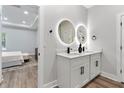 Modern bathroom featuring dual sinks with stylish vanities, round mirrors, and wood-look flooring at 7088 Sw 128Th Terrace Rd, Dunnellon, FL 34432
