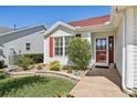 Inviting front entrance with colorful landscaping and a decorative red front door at 750 Evelynton Loop, The Villages, FL 32162