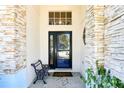 View of entryway with stone siding, covered porch, seating bench and decorative door at 8051 Saint James Way, Mount Dora, FL 32757