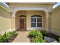 Inviting entryway with a wood door, arched window, and manicured landscaping at 859 Parksville Path, The Villages, FL 32162