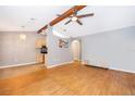 Open-concept living room seamlessly connects to kitchen area, with hardwood flooring, ceiling fan and beamed vaulted ceiling at 1306 Vine St, Leesburg, FL 34748