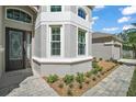 Home exterior featuring meticulously landscaped front yard with brick walkway, mature plantings, and gray stucco at 15803 Fairview Pt, Tavares, FL 32778