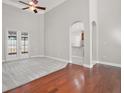 Spacious living room featuring wood floors, high ceilings, fan, and french doors leading to outdoor space at 15803 Fairview Pt, Tavares, FL 32778