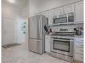 Kitchen with stainless steel appliances including refrigerator, range, and microwave, adjacent to the entryway at 1829 Foxwood Ln, The Villages, FL 32162