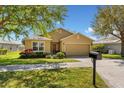 Charming single-story home featuring a well-manicured lawn, lovely landscaping, and attached garage at 202 Compass Rose Dr, Groveland, FL 34736
