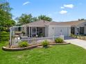 Charming home featuring a white picket fence, a screened patio, and lush landscaping, offering a welcoming outdoor space at 2234 Braxton St, The Villages, FL 32162