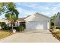 Single-story home featuring a well-manicured lawn, palm tree, and a two-car garage at 891 Lucky Ln, The Villages, FL 32162