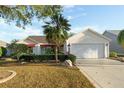 Charming single-story home with a well-manicured lawn, palm tree, and a two-car garage at 891 Lucky Ln, The Villages, FL 32162