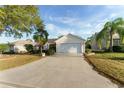 Single-story home with a well-manicured lawn, palm trees, and a two-car garage at 891 Lucky Ln, The Villages, FL 32162