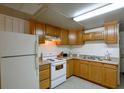 Well-lit kitchen with white appliances, light wood cabinets, and a double basin stainless steel sink at 10301 Us Highway 27 # 84, Clermont, FL 34711
