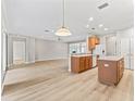 Bright, open-concept kitchen with wood cabinets, white appliances, a center island and light wood flooring at 11759 Se 91St Cir, Summerfield, FL 34491