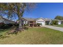Inviting single-story home featuring a well-maintained lawn, mature shade tree and appealing curb appeal at 1417 Forest Acres Dr, The Villages, FL 32162