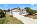 Inviting single-story home with well-maintained lawn, concrete driveway, and attached two-car garage at 1773 Hallandale Ln, The Villages, FL 32162
