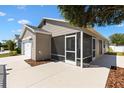 Side view of home showcasing the screened patio, concrete walkway, and attached two-car garage at 1773 Hallandale Ln, The Villages, FL 32162