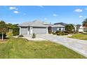 Beautiful home with a lush front lawn, paver driveway, and a two-car garage, set in a serene neighborhood at 2213 Evans Prairie Trl, The Villages, FL 32163