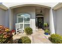 Inviting front porch with a rocking chair, potted plants, and a wreath on the front door at 2213 Evans Prairie Trl, The Villages, FL 32163