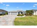 Charming home featuring a well-manicured lawn, mature landscaping, a stone driveway, and a three-car garage at 2213 Evans Prairie Trl, The Villages, FL 32163