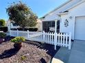 Close-up of a home's front lawn with decorative shrubs, a white picket fence, and address number at 2569 Errol Ter, The Villages, FL 32162