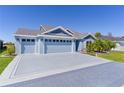 Exterior elevation with large driveway, well-kept lawn and landscaping and a two car garage at 6444 Mcknight Loop, The Villages, FL 34762