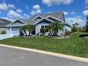 Inviting single-story home with lush green lawn and tropical landscaping at 6444 Mcknight Loop, The Villages, FL 34762