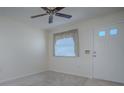 Bright, carpeted living room featuring a ceiling fan, window, and entry door at 701 Cottage Park Ln, Leesburg, FL 34748