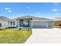 Charming home featuring a landscaped lawn, neutral paint, three car garage, and covered porch at 7250 Trundle Ter, The Villages, FL 34762