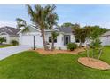 Charming single-story home featuring a manicured lawn with rock landscaping, a palm tree and a spacious two car garage at 7539 Hagemeyer Pl, The Villages, FL 34762