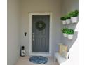 Inviting front door with a decorative wreath, potted plants, and a cozy bench for added charm at 916 Carmillion Ct, Groveland, FL 34736