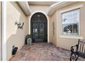 Elegant entrance with brick-paved patio, arched doorway, and decorative wall art at 10199 Mainsail Dr, Oxford, FL 34484