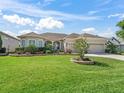 Well-maintained front yard with lush green grass, beautiful landscaping, and a spacious three-car garage at 12136 Se 176Th Loop, Summerfield, FL 34491