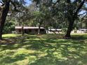 Well-maintained front yard with lush green grass, mature trees, and a charming single story house at 136 S Commercial St, Coleman, FL 33521