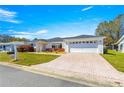 Single-story home with long paved driveway and well-manicured lawn, brick accents, and an attached two-car garage at 17594 Se 95Th Cir, Summerfield, FL 34491