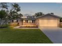 Charming single-story home with well-manicured lawn, gray siding, and a two-car garage at dusk at 17965 Se 107Th Ct, Summerfield, FL 34491