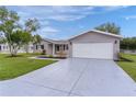 A tidy single-story home with a well-maintained lawn, gray siding, and an attached two-car garage at 17965 Se 107Th Ct, Summerfield, FL 34491