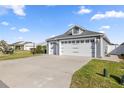 Three-car garage with carriage doors on a well-maintained, light blue home at 1853 Pasqua Pl, The Villages, FL 32163