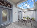 Relaxing screened patio featuring a cozy seating area with a table and chairs and double door access to the home at 22247 Draw Bridge Dr, Leesburg, FL 34748
