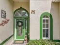 Close-up of a decorative green front door with glass details, wreath, and plants at 24112 Robinwood St, Leesburg, FL 34748