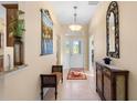 Bright foyer featuring tile flooring, a decorative mirror, and a view of the front door at 2428 Maverick Way, The Villages, FL 32162