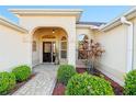 Inviting front entrance with decorative plants, brick pathway, and arched doorway at 2428 Maverick Way, The Villages, FL 32162