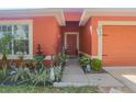 Inviting front entrance featuring vibrant landscaping, a charming fountain, and a warm colored exterior at 2442 Foxhollow Rd, Tavares, FL 32778