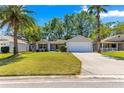Landscaped single-story home featuring a two-car garage and well-manicured front lawn at 2488 Ansley Path, The Villages, FL 32162