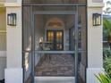 Close up of a screened front porch with brick flooring, lighting sconces, and seating area at 5813 Lake Emma Ct, Groveland, FL 34736