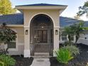 Beautifully appointed arched front porch with brick flooring, lighting sconces, and seating area at 5813 Lake Emma Ct, Groveland, FL 34736